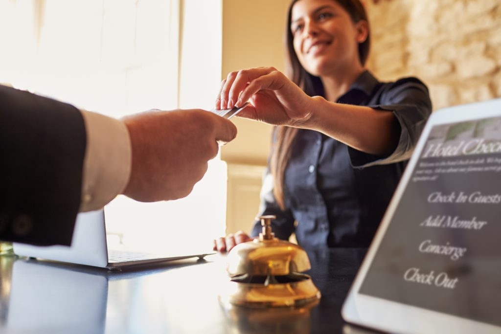 guest takes room key card at check in desk of hotel, close up